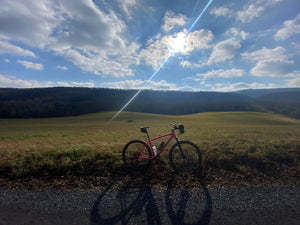 Pink bicycle on a dirt path with a scenic view of rolling hills and blue sky in Rothrock State Forest - photo by Purple Lizard Maps
