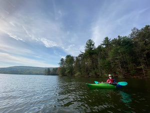 Person kayaking on Colyer Lake PA a lake with trees and mountains in the background on the Purple Lizard Map